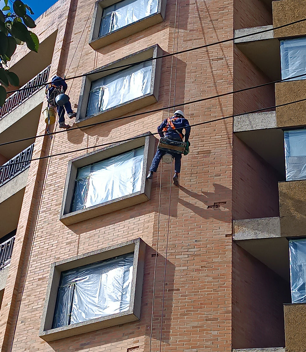 hombres lavando fachada edificio bogota